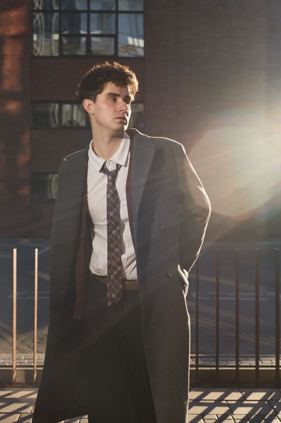 Backlit street portrait, sun flare across a grey overcoat