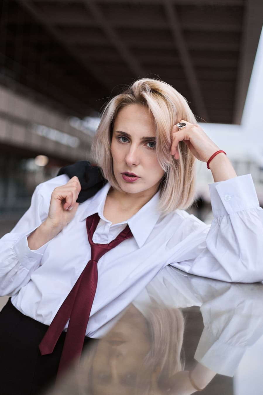 Street portrait over a reflective surface, white shirt and burgundy tie