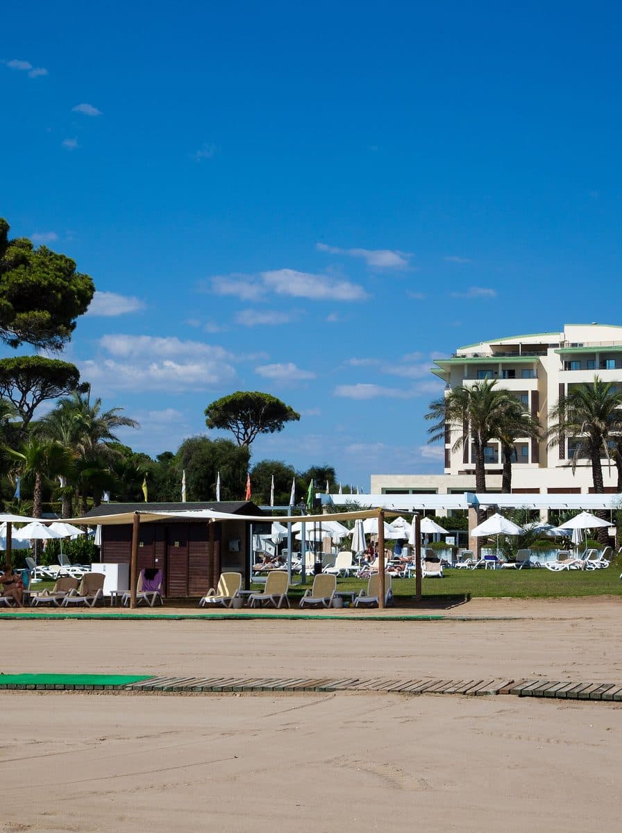 Belek resort beach with palms, umbrellas and hotels behind, Antalya
